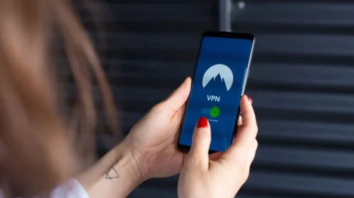 Close-up of a woman's hands using a VPN app on a smartphone, emphasizing digital security.
